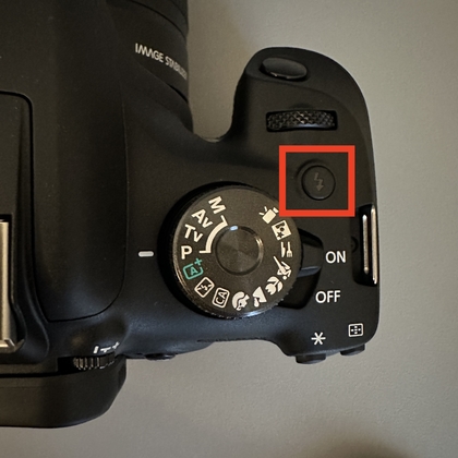 Op de flitsknop drukken op een Canon-camera